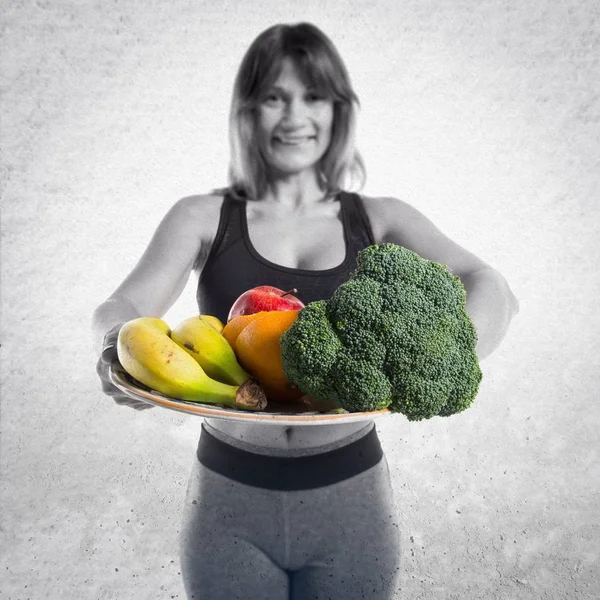 Спортивна жінка тримає фрукти та овочі — стокове фото