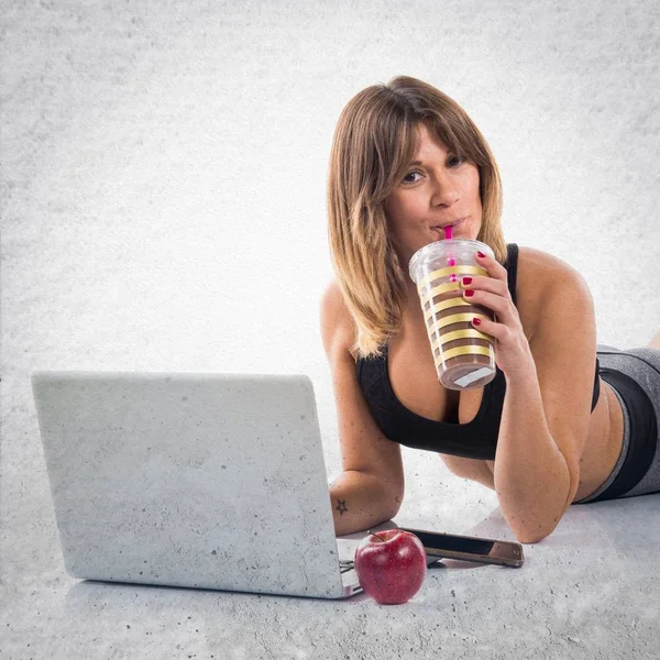 Sportlerin arbeitet mit Laptop und trinkt Sportgetränk — Stockfoto