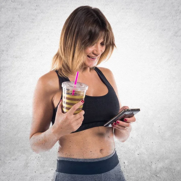 Sport woman with her mobile and her sport drink
