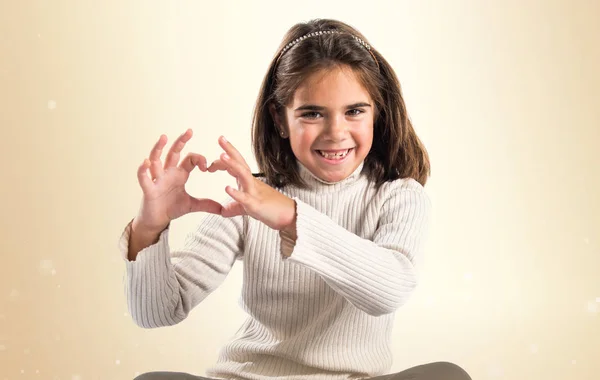 Kleines brünettes Mädchen macht ein Herz mit ihren Händen — Stockfoto