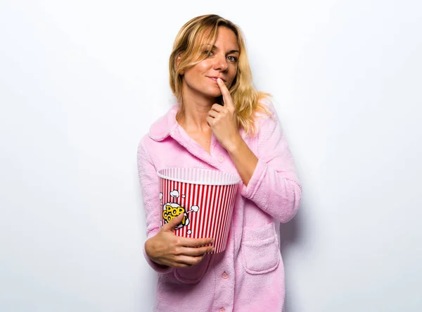 Szép szőke nő evés popcorns rózsaszín pongyolában — Stock Fotó