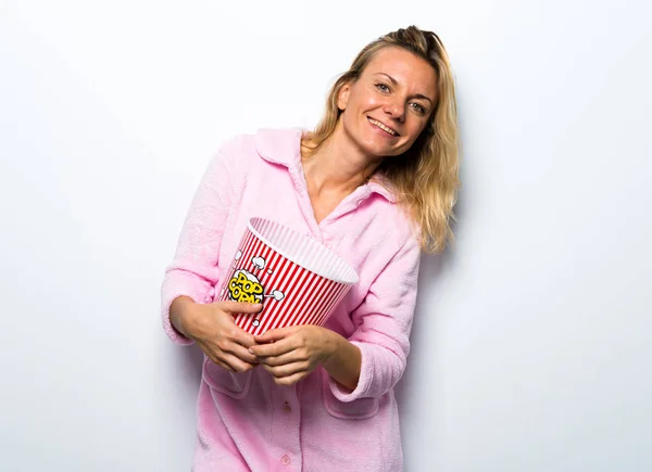 Hübsche blonde Frau im pinkfarbenen Morgenmantel, die Popcorn isst — Stockfoto