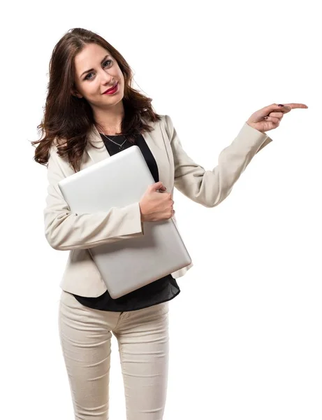 Mujer de negocios bastante joven con el ordenador portátil y apuntando a la lateral — Foto de Stock