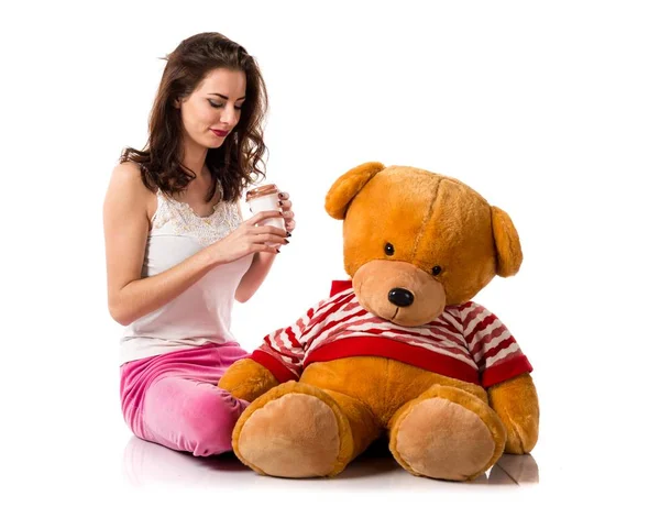 Girl with pajamas holding a take away coffee and playing with stuffed animal — Stock Photo, Image