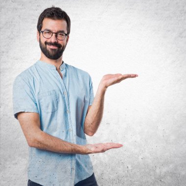 Mavi gözlüklü bir şey sunmak yakışıklı adam