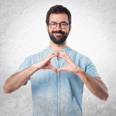 Yakışıklı adam mavi gözlük elleri ile bir kalp yapma
