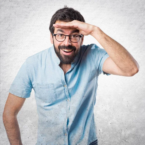 Bir şey gösterilen mavi gözlüklü yakışıklı adam