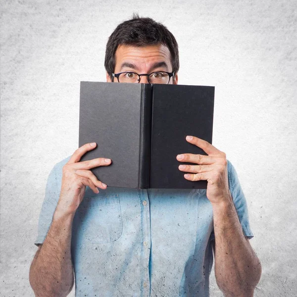 Handsome man with blue glasses reading book — Stock Photo, Image