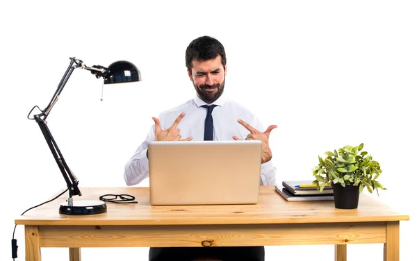 Empresário em seu escritório fazendo gesto chifre — Fotografia de Stock