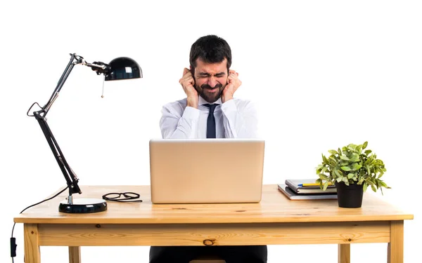 Zakenman in zijn kantoor die betrekking hebben op zijn oren — Stockfoto