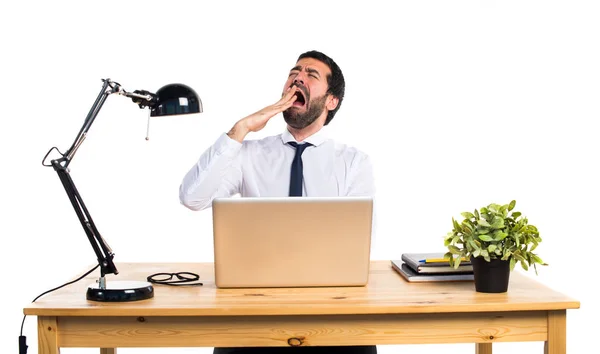 Empresário em seu escritório bocejando — Fotografia de Stock