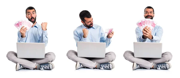 Homem com laptop levando um monte de dinheiro — Fotografia de Stock