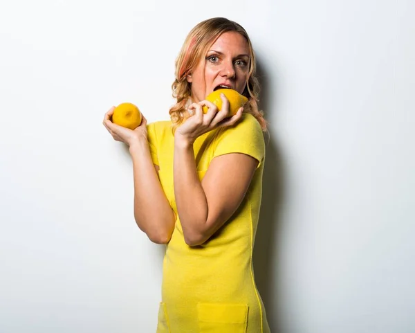 Beautiful blonde woman holding lemons — Stock Photo, Image