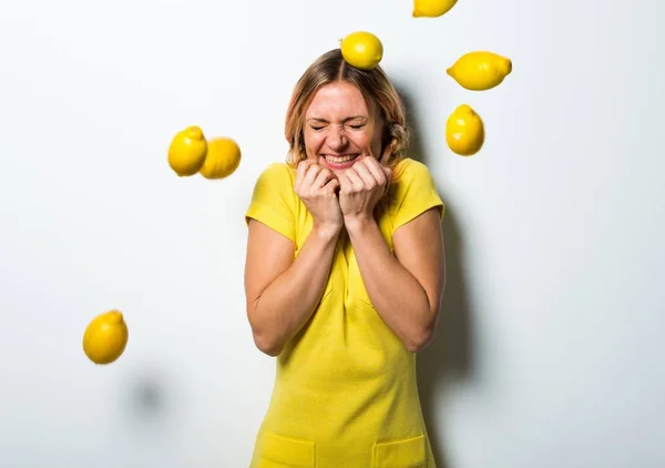 Schöne blonde Frau hält Zitronen — Stockfoto