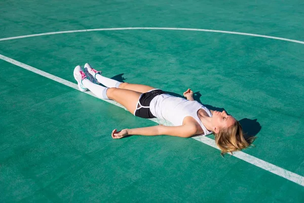 Mujer bonita en el campo de fútbol descansando en el suelo — Foto de Stock