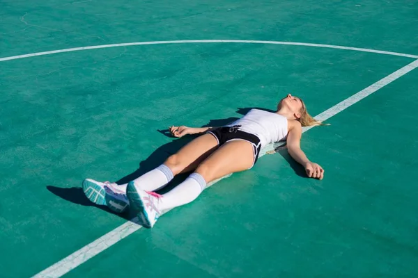Csinos nő feküdjön a padlóra focipálya — Stock Fotó