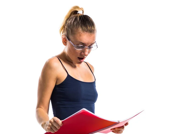 Linda menina da escola loira sentada em muitos livros e segurando notas da faculdade e fazendo gesto surpresa — Fotografia de Stock