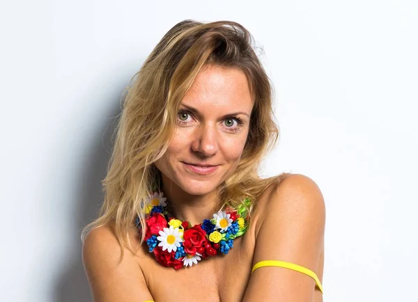 Mulher modelo bonito posando em estúdio com um colar de flores coloridas — Fotografia de Stock