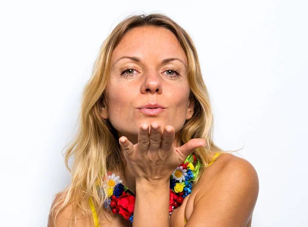 Linda mujer modelo con un collar de flores de colores enviando un beso — Foto de Stock