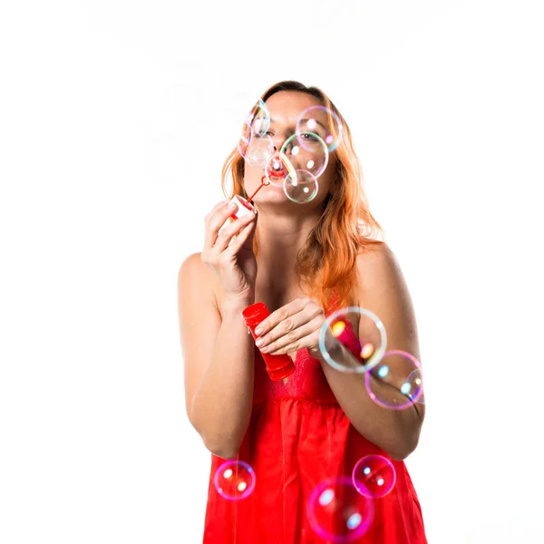Mujer hermosa con el pelo naranja burbujas que soplan — Foto de Stock