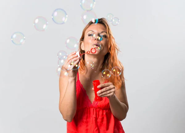 Krásná žena s oranžové vlasy foukat bubliny — Stock fotografie