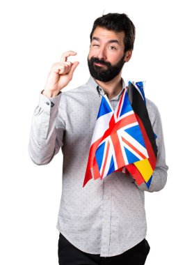 Birçok bayrak tutan ve küçük işareti yaparak sakallı yakışıklı adam