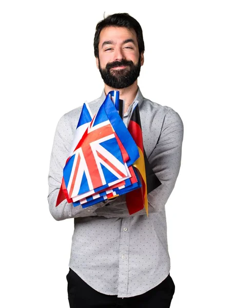 Homem bonito com barba segurando muitas bandeiras — Fotografia de Stock