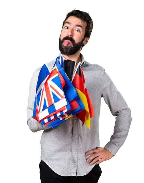 Homem bonito com barba segurando muitas bandeiras e fazendo uma piada — Fotografia de Stock
