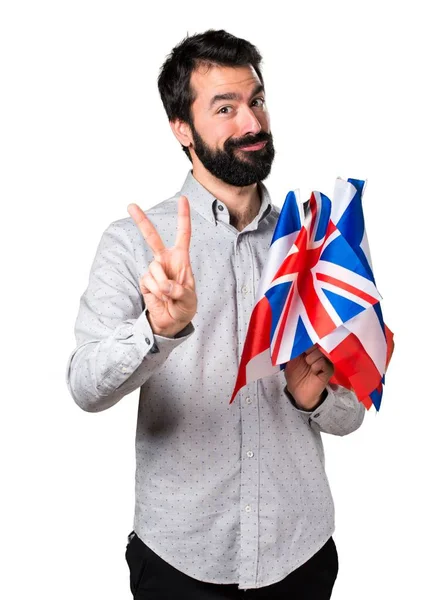 Bonito homem com barba segurando muitas bandeiras e contando duas — Fotografia de Stock