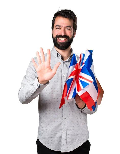 Hombre guapo con barba sosteniendo muchas banderas y cinco —  Fotos de Stock