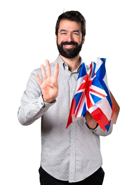 Hombre guapo con barba sosteniendo muchas banderas y contando cuatro —  Fotos de Stock