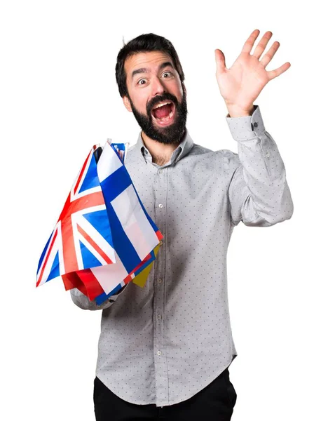 Stilig man med skägg hålla många flaggor och salutera — Stockfoto