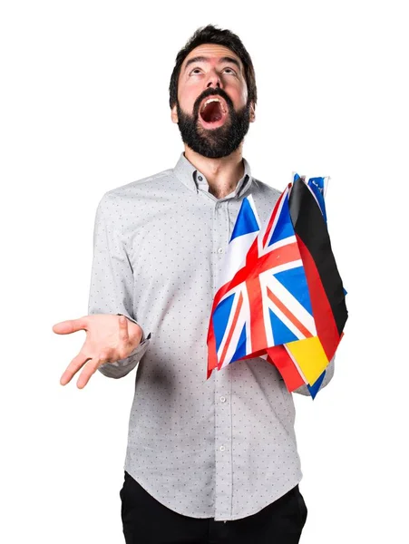 Stilig man med skägg hålla många flaggor och gör överraskning gest — Stockfoto