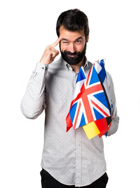 Birçok bayrak tutan ve düşünme sakallı yakışıklı adam — Stok fotoğraf