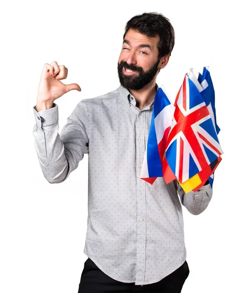 Homem bonito com barba segurando muitas bandeiras orgulhoso de si mesmo — Fotografia de Stock