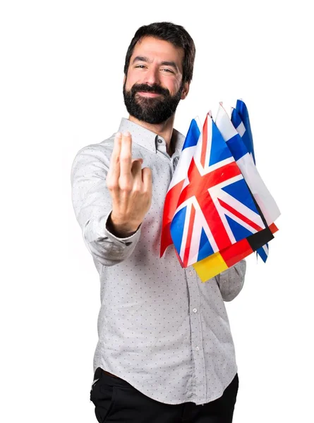 Stilig man med skägg hålla många flaggor och kommer gest — Stockfoto