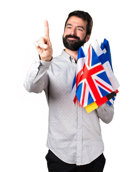 Hombre guapo con barba sosteniendo muchas banderas y tocando en la pantalla transparente —  Fotos de Stock