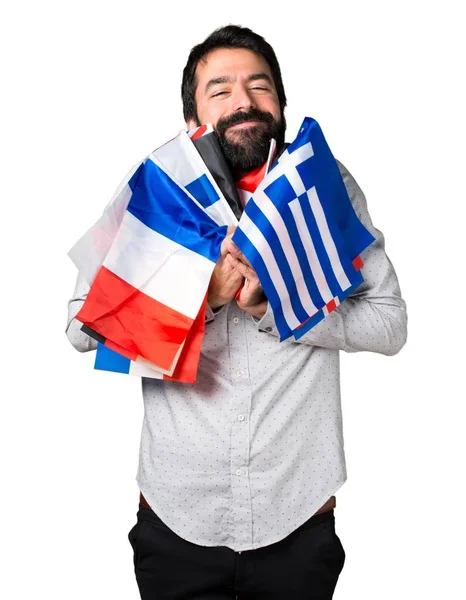 Gelukkig knap man met baard houden vele vlaggen — Stockfoto