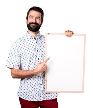 Boş bir afiş tutarak sakallı yakışıklı esmer adam