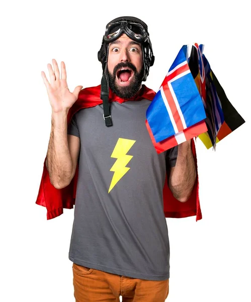 Super-herói com muitas bandeiras fazendo gesto surpresa — Fotografia de Stock