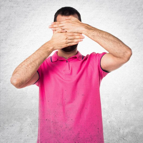 Człowiek z kolorowe ubrania ukrywszy twarz na szary teksturowanej bac — Zdjęcie stockowe
