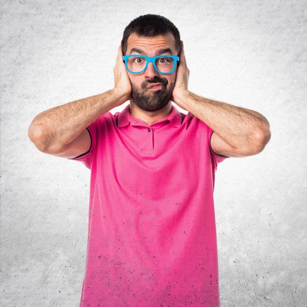 Mannen med färgglada kläder som täcker öronen på grå texturerat bac — Stockfoto