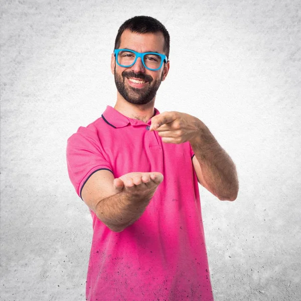 Homem com roupas coloridas segurando algo no bac texturizado cinza — Fotografia de Stock