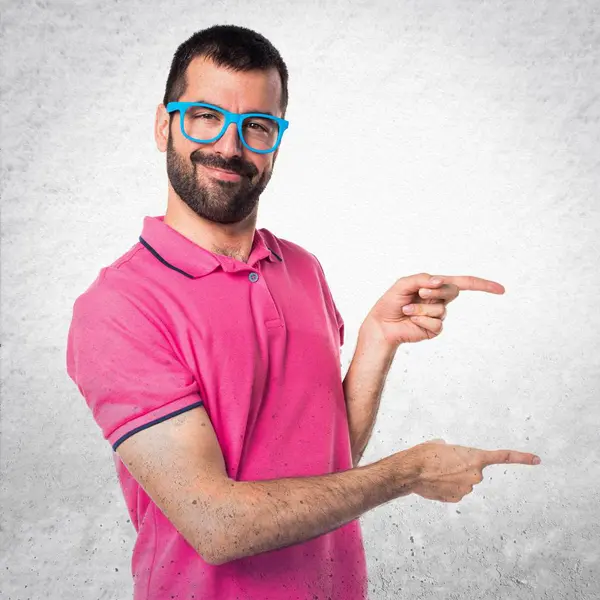 Homme avec des vêtements colorés pointant vers le côté sur textur gris — Photo