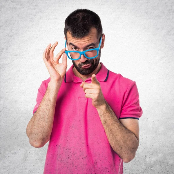 Homme avec des vêtements colorés montrant quelque chose sur bac texturé gris — Photo