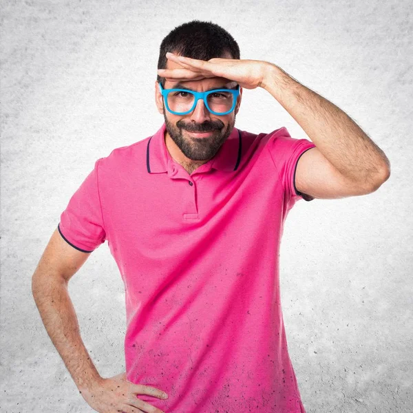 Homme avec des vêtements colorés montrant quelque chose sur bac texturé gris — Photo