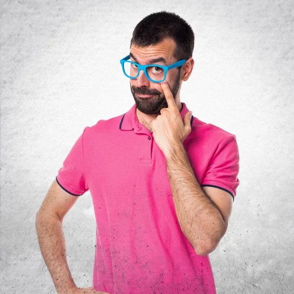 Homme avec des vêtements colorés montrant quelque chose sur bac texturé gris — Photo