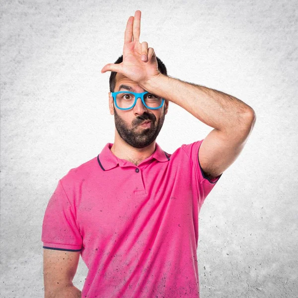 Homme avec des vêtements colorés faisant signe stupide sur bac texturé gris — Photo