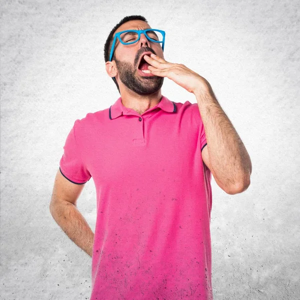 Homme avec des vêtements colorés bâillant sur fond gris texturé — Photo