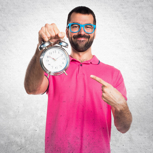 Man with colorful clothes holding vintage clock on grey textured